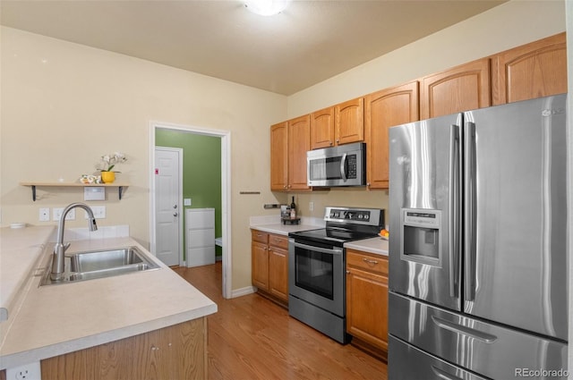 kitchen with stainless steel appliances, a sink, light wood-style floors, light countertops, and open shelves