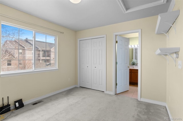 unfurnished bedroom featuring a closet, visible vents, light carpet, and baseboards