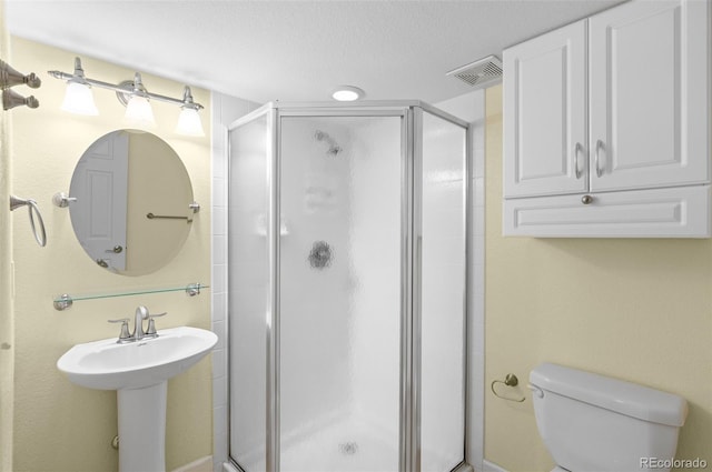 full bathroom with visible vents, toilet, a stall shower, a sink, and a textured ceiling