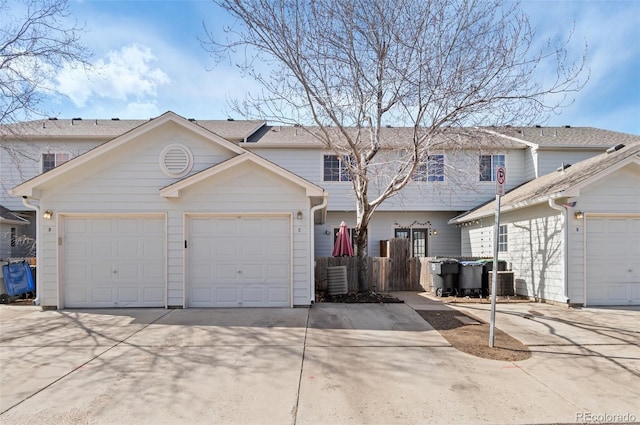 view of front facade with an attached garage, driveway, and fence