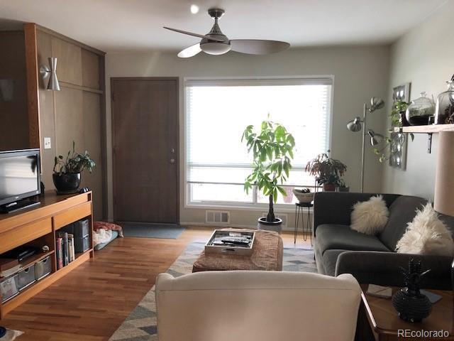 living area with a ceiling fan, visible vents, and wood finished floors