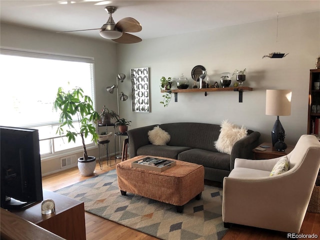 living area featuring a ceiling fan, a healthy amount of sunlight, visible vents, and wood finished floors