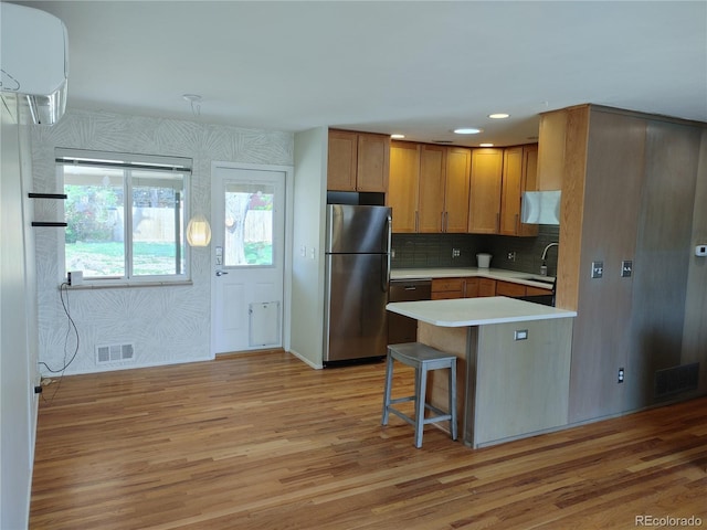 kitchen with light wood finished floors, visible vents, freestanding refrigerator, a peninsula, and light countertops