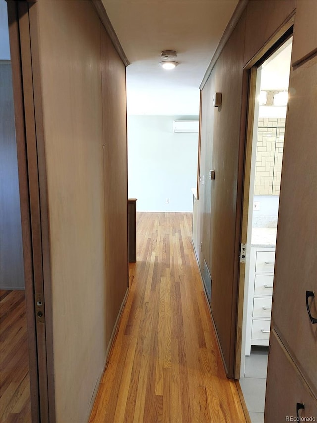 hall featuring light wood-type flooring, visible vents, and an AC wall unit