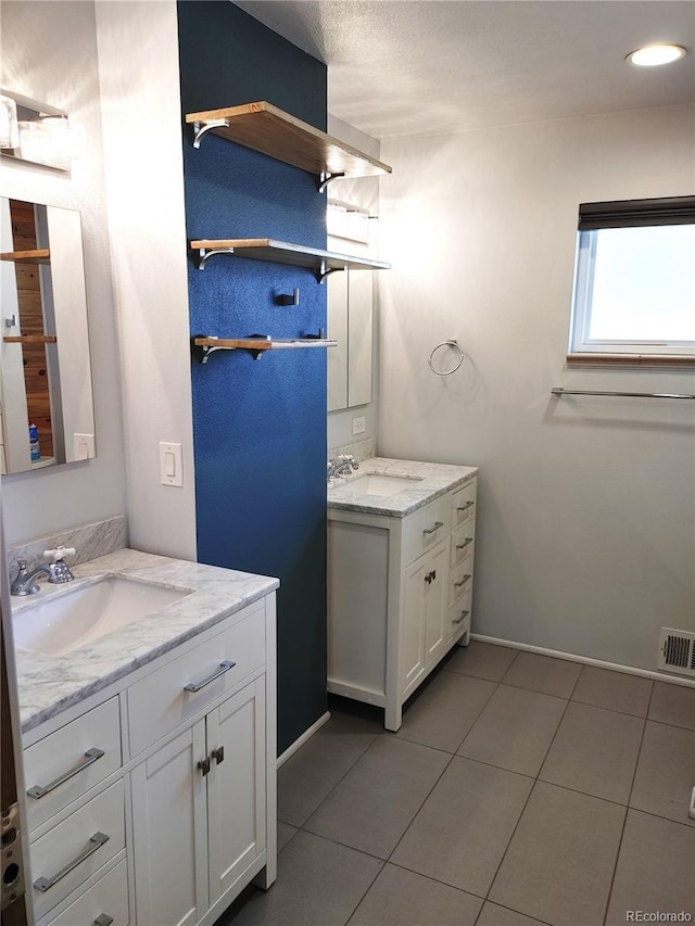 bathroom featuring two vanities, a sink, and tile patterned floors