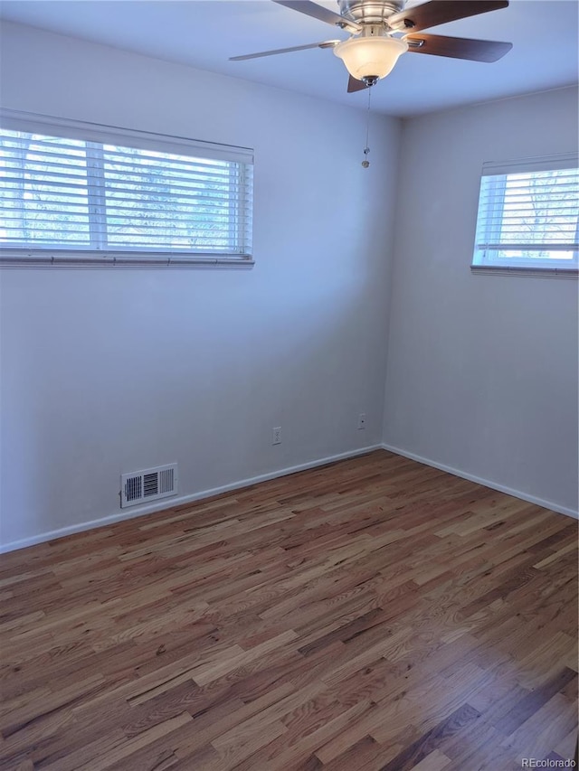 empty room featuring baseboards, ceiling fan, visible vents, and wood finished floors