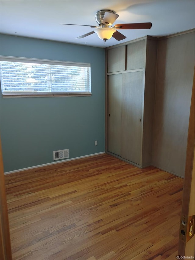 unfurnished bedroom featuring baseboards, visible vents, ceiling fan, light wood-type flooring, and a closet