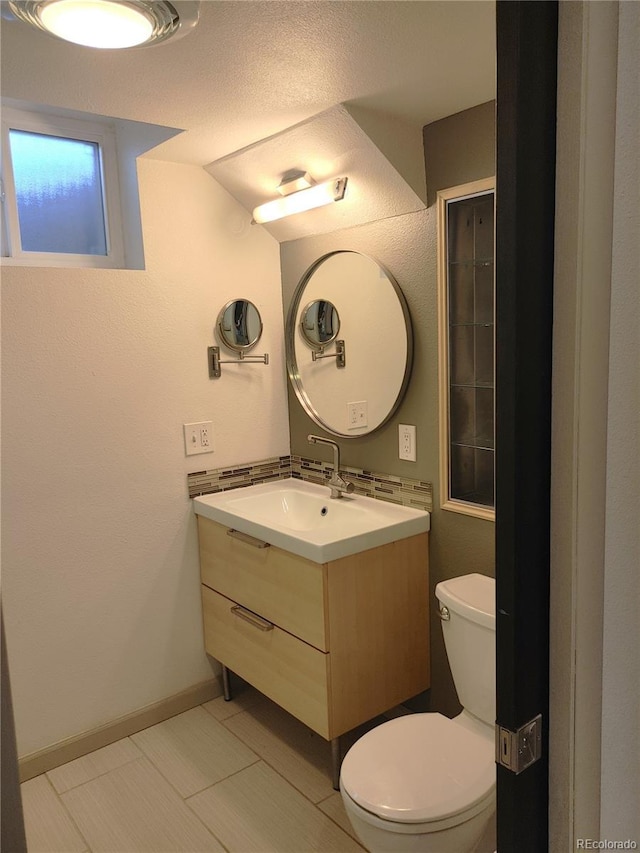 half bath with vanity, toilet, and baseboards