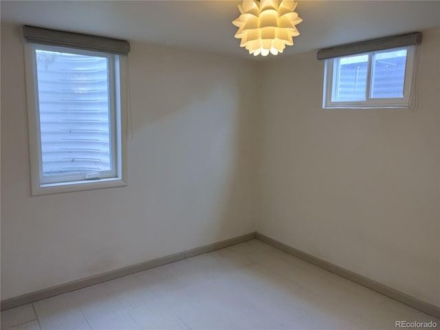 empty room with a chandelier, baseboards, and light floors