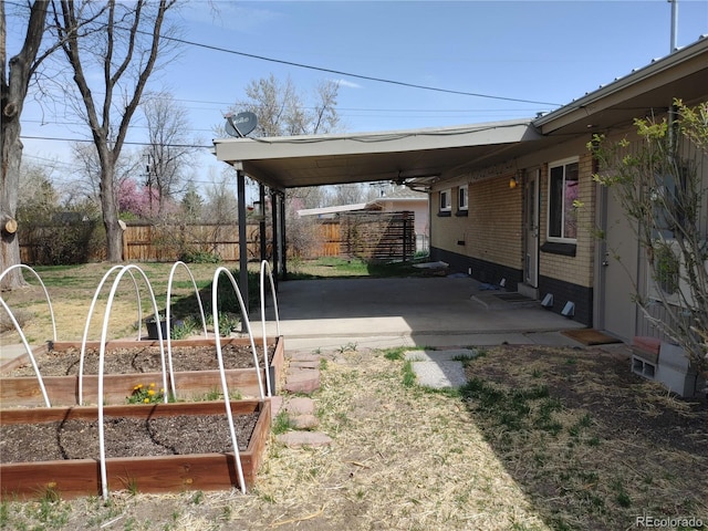 view of yard featuring fence, a vegetable garden, and an attached carport