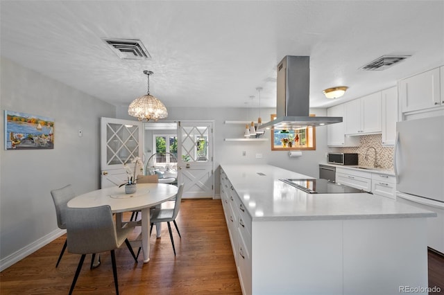 kitchen featuring island range hood, white cabinetry, decorative light fixtures, white fridge, and dark hardwood / wood-style floors