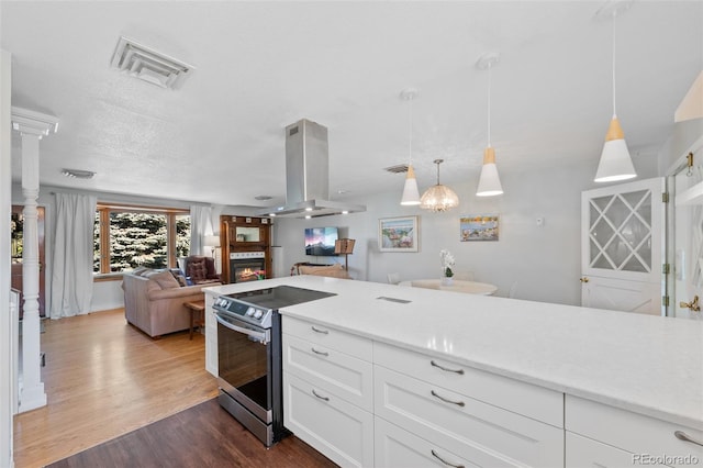 kitchen featuring island exhaust hood, hanging light fixtures, stainless steel electric range, white cabinets, and dark hardwood / wood-style floors