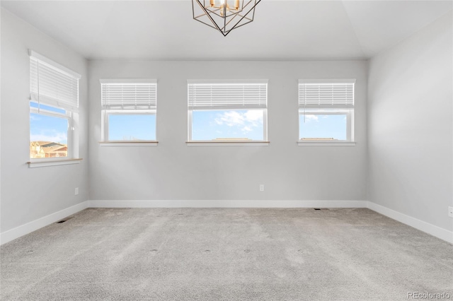 carpeted spare room featuring a chandelier