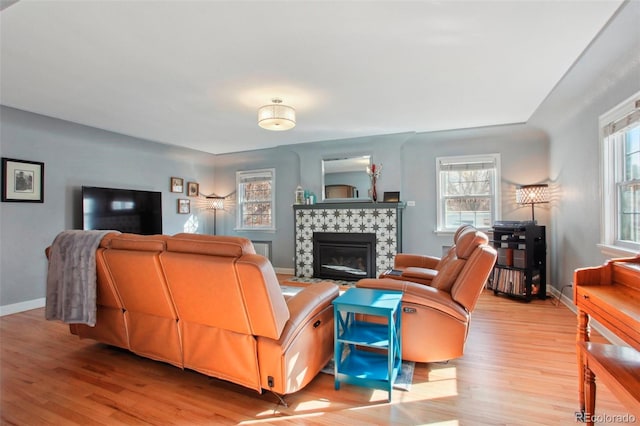 8001 W 57th Ave, Arvada, CO 80002 - living room with light wood-style flooring, a tiled fireplace, and baseboards