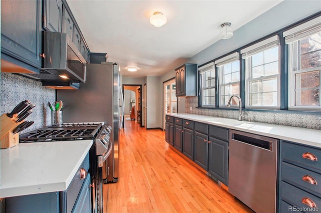 8001 W 57th Ave, Arvada, CO 80002 - kitchen featuring appliances with stainless steel finishes, a sink, light countertops, tasteful backsplash, and light wood finished floors