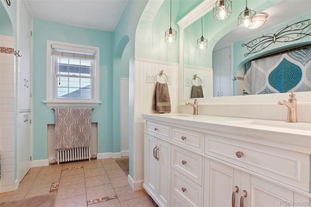 8001 W 57th Ave, Arvada, CO 80002 - bathroom with double vanity, radiator heating unit, tile patterned floors, and baseboards