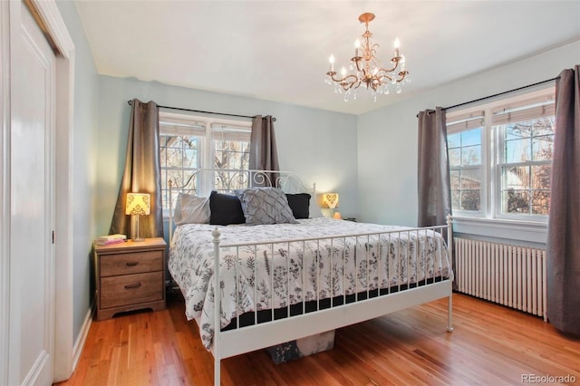 8001 W 57th Ave, Arvada, CO 80002 - bedroom featuring radiator heating unit, light wood finished floors, a chandelier, and multiple windows