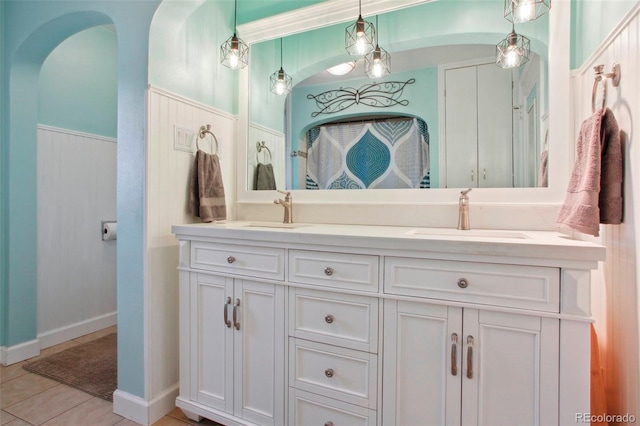 8001 W 57th Ave, Arvada, CO 80002 - bathroom with double vanity, tile patterned floors, a wainscoted wall, and baseboards