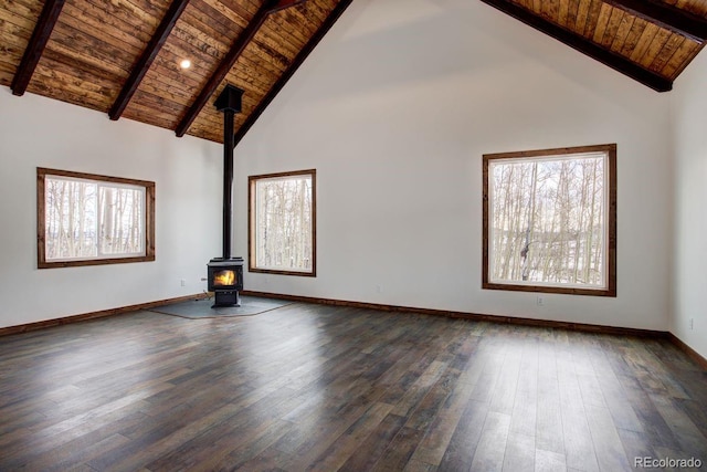 spare room with a wood stove, wood ceiling, baseboards, and dark wood-style flooring