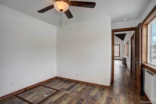 empty room featuring radiator, a ceiling fan, baseboards, and wood finished floors