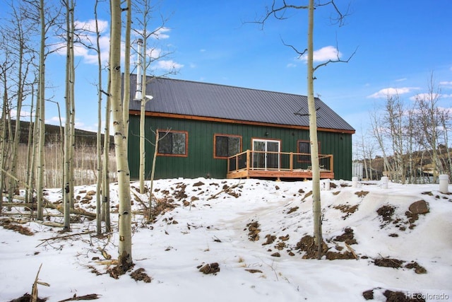 snow covered house with metal roof and a wooden deck