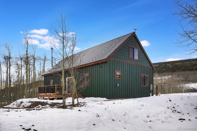 exterior space featuring a garage, metal roof, a deck, and board and batten siding