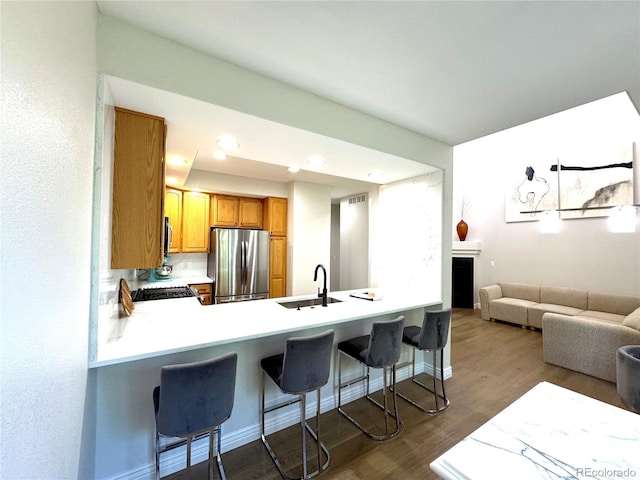 12743 W Bowles Pl, Littleton, CO 80127 - kitchen featuring freestanding refrigerator, a sink, a breakfast bar area, dark wood-style floors, and a peninsula