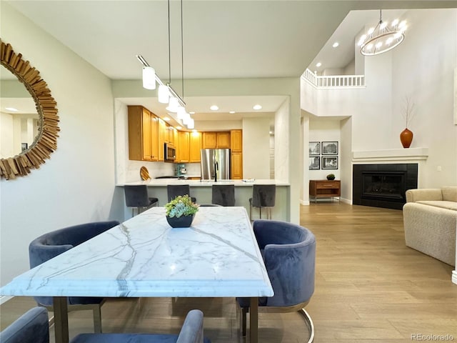 12743 W Bowles Pl, Littleton, CO 80127 - dining area featuring light wood-style floors, recessed lighting, a tile fireplace, a chandelier, and baseboards