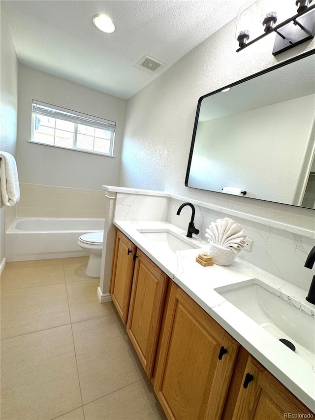 12743 W Bowles Pl, Littleton, CO 80127 - bathroom featuring toilet, double vanity, tile patterned flooring, a bathtub, and a textured ceiling