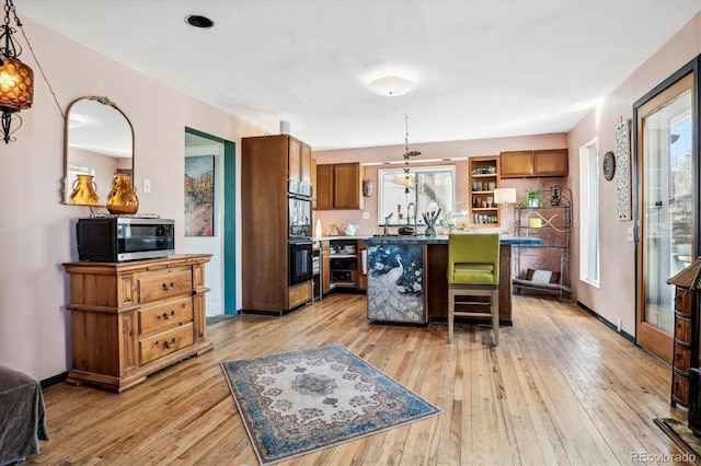 3 S Newton St, Denver, CO 80219 - kitchen with stainless steel microwave, light wood-style flooring, open shelves, a center island, and hanging light fixtures