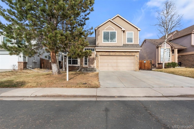 traditional-style house with brick siding, an attached garage, concrete driveway, and fence