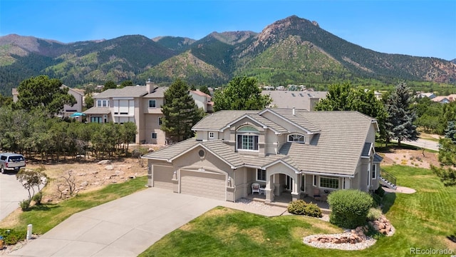 view of front facade featuring a garage, a mountain view, and a front lawn