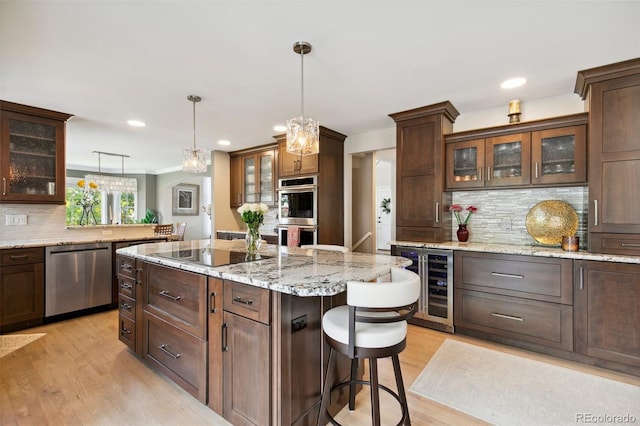 kitchen with wine cooler, a breakfast bar, a center island, pendant lighting, and stainless steel appliances