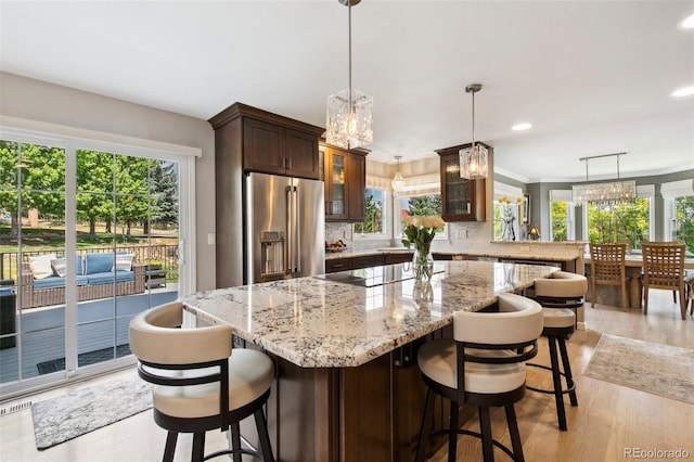 kitchen with black electric cooktop, hanging light fixtures, high quality fridge, and a kitchen breakfast bar