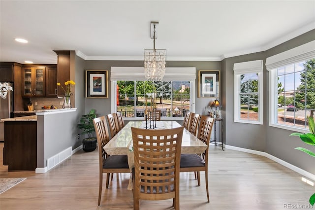 dining area featuring crown molding, a chandelier, and light hardwood / wood-style floors