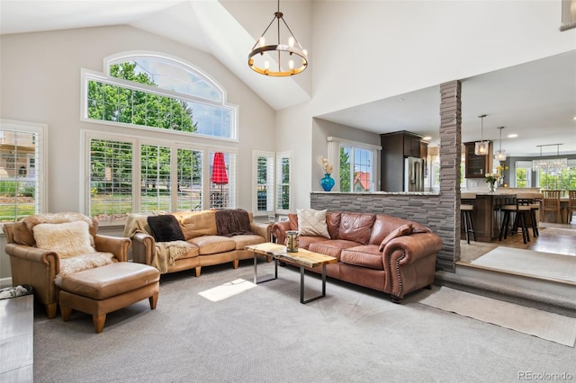 living room featuring a notable chandelier, light colored carpet, and high vaulted ceiling