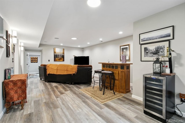 living room featuring indoor bar, beverage cooler, and light hardwood / wood-style flooring