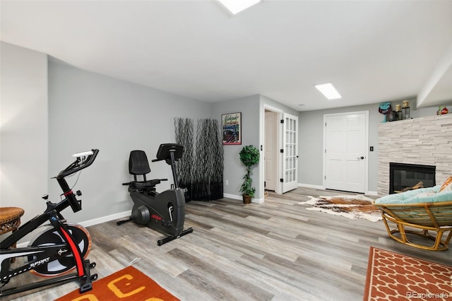 exercise room with a fireplace and light hardwood / wood-style floors