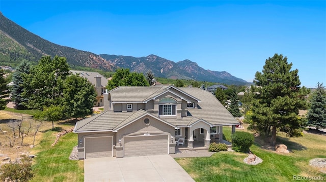 view of front of house featuring a mountain view, a garage, a front lawn, and a porch