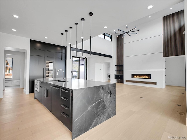 8132 Galileo Way, Littleton, CO 80125 - kitchen featuring a spacious island, a sink, light wood finished floors, modern cabinets, and open floor plan