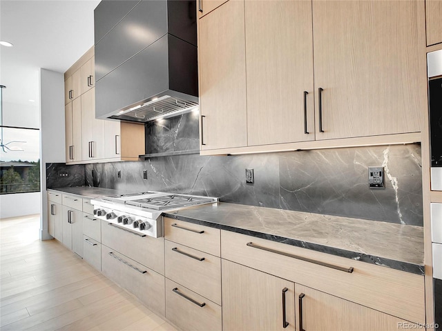 8132 Galileo Way, Littleton, CO 80125 - kitchen with stainless steel gas stovetop, decorative backsplash, dark stone countertops, custom range hood, and light brown cabinetry