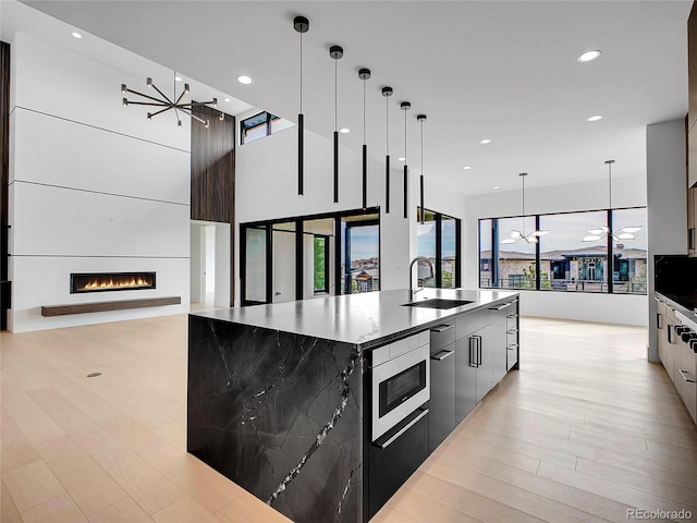 8132 Galileo Way, Littleton, CO 80125 - kitchen featuring stainless steel microwave, a chandelier, a sink, a large island, and modern cabinets