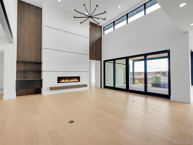 8132 Galileo Way, Littleton, CO 80125 - unfurnished living room with a warm lit fireplace, wood finished floors, recessed lighting, and an inviting chandelier