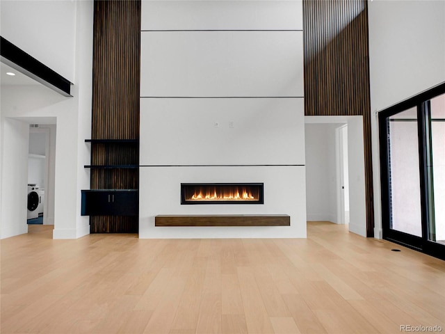 8132 Galileo Way, Littleton, CO 80125 - unfurnished living room with a towering ceiling, washer / dryer, a lit fireplace, and wood finished floors