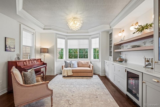 living area with a textured ceiling, a tray ceiling, dark wood-style flooring, and ornamental molding