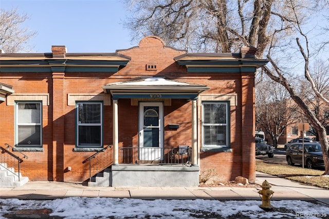 view of front facade featuring brick siding and a chimney