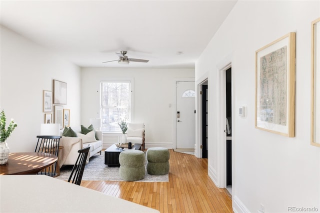 living room with light wood-type flooring, baseboards, and ceiling fan