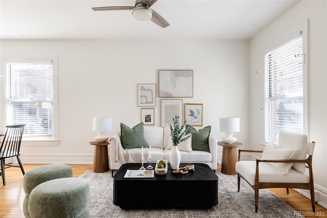 living area with light wood-style floors, baseboards, and ceiling fan
