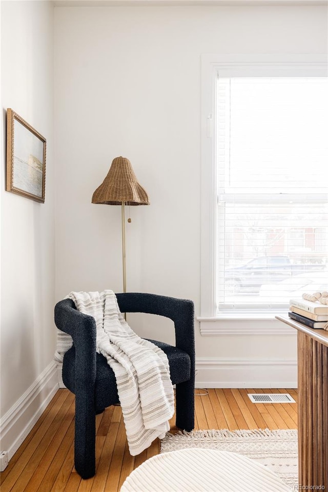 living area with baseboards, hardwood / wood-style floors, and visible vents