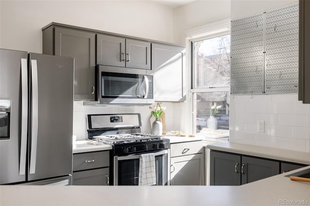 kitchen featuring backsplash, light countertops, stainless steel appliances, and gray cabinetry